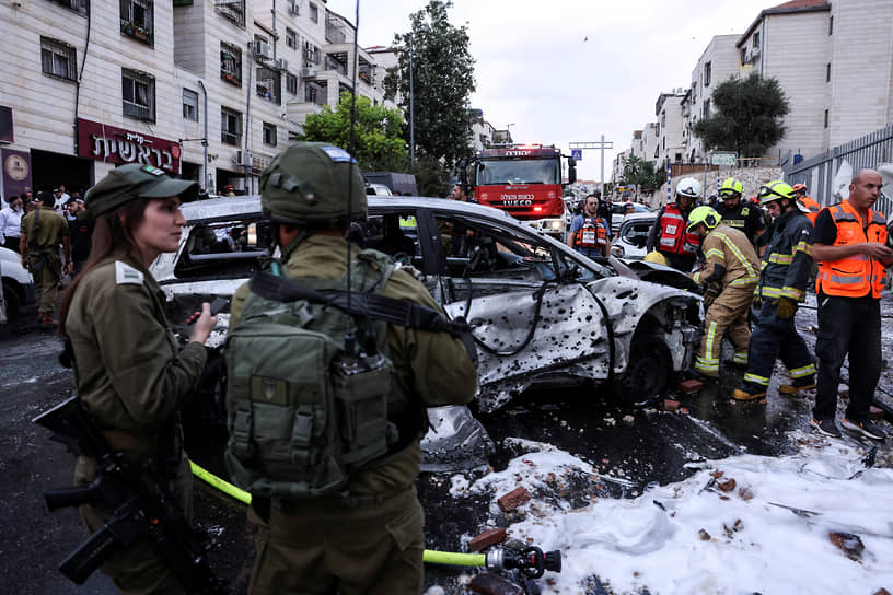 Сотрудники службы безопасности Израиля у сгоревшего автомобиля в поселении Бейтар-Илит 
