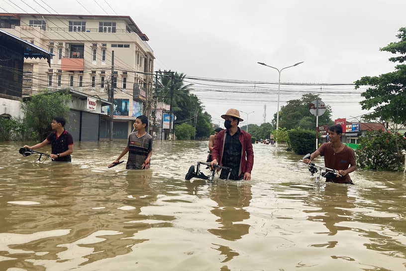 Янгона, Мьянма. Местные жители на затопленной дороге после наводнения, вызванного сильными муссонными дождями 