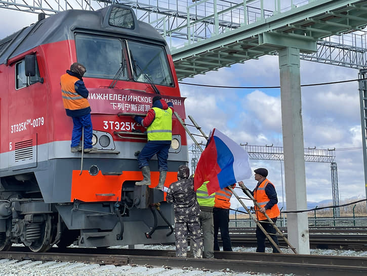 Российский флаг устанавливают на поезде перед отправлением по новому железнодорожному мосту Нижнеленинское-Тунцзян (апрель 2022 года)