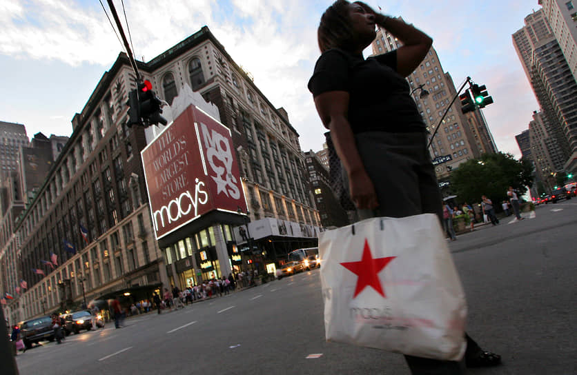 Покупательница с пакетом Macy's проходит мимо универмага Macy's в Нью-Йорке