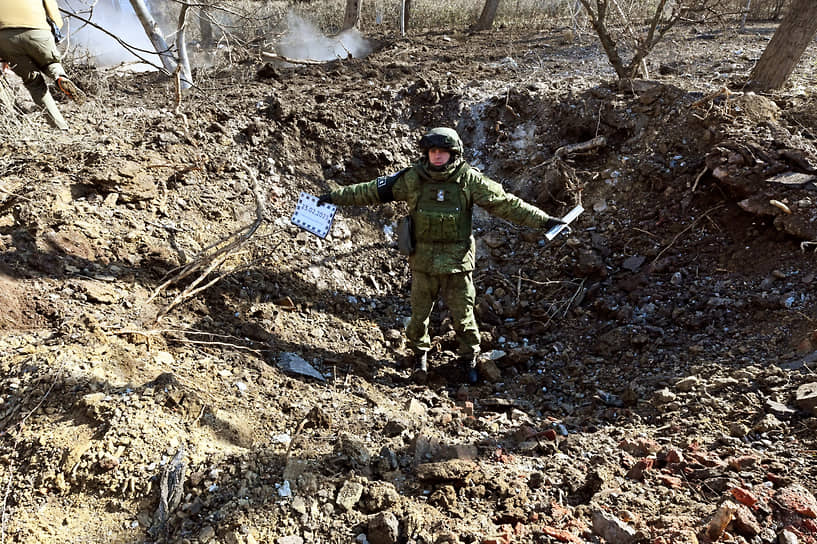 Сотрудник Совместного центра контроля и координации ДНР в воронке от снаряда в Донецке