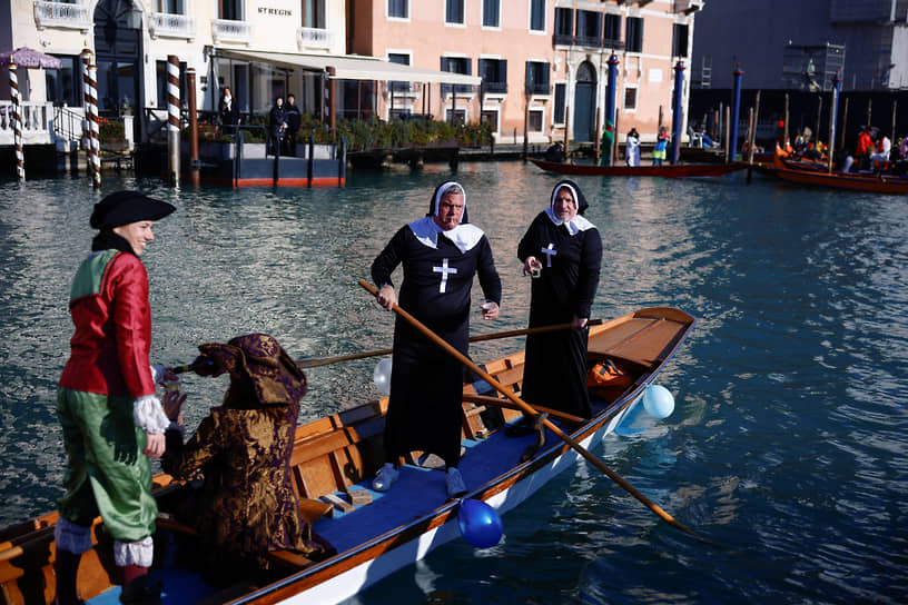 Участники карнавала плывут на гондоле в костюмах монахинь