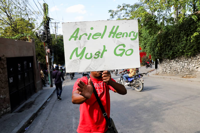 Демонстрант держит плакат с требованием отставки премьер-министра Гаити Ариэля Анри