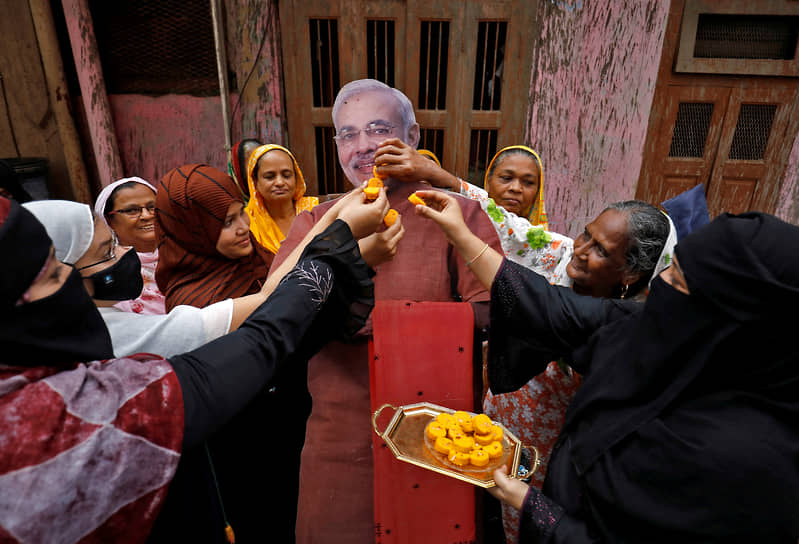 Мусульманские женщины предлагают сладости картонному изображению премьер-министра Индии Нарендры Моди