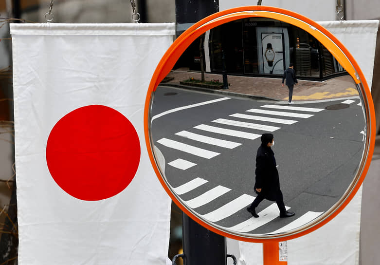Токио. Отражение пешеходов в зеркале на автомобильном перекрестке   