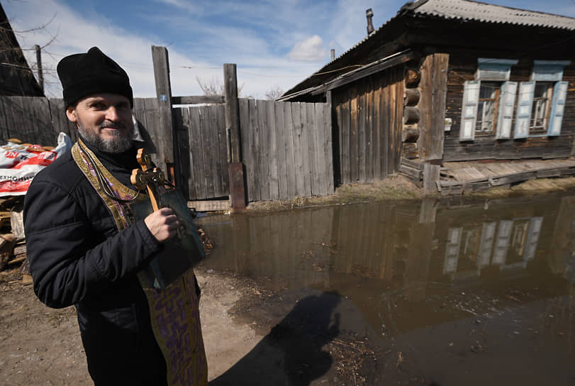 Священнослужитель во время молитвы у ворот жилого частного дома в районе села Звериноголовское