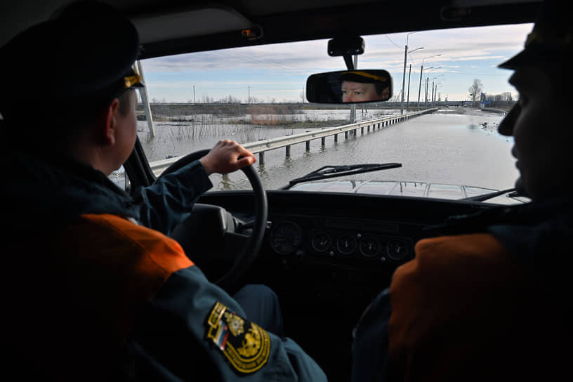 Сотрудники МЧС России в автомобиле на фоне перелива реки Тобол через шоссе