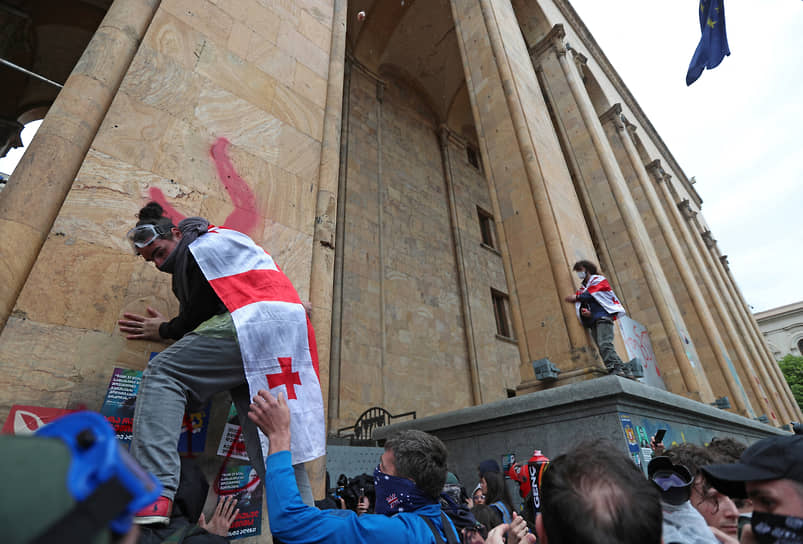 Демонстрант взбирается по стене грузинского парламента