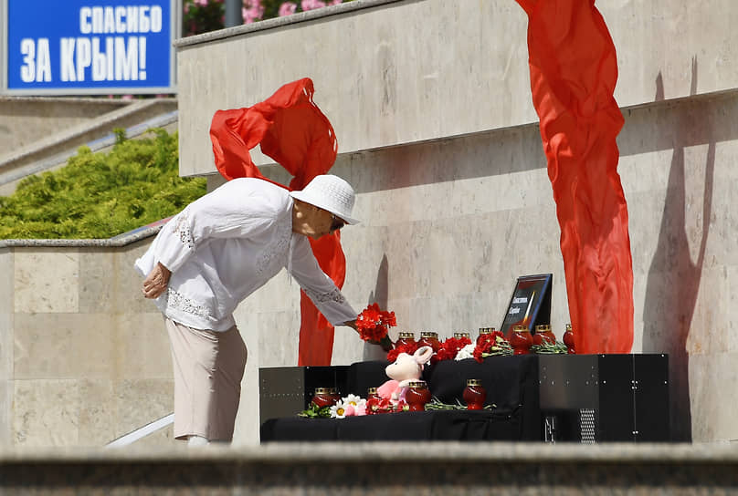 Женщина возлагает цветы к стихийному мемориалу в Алуште