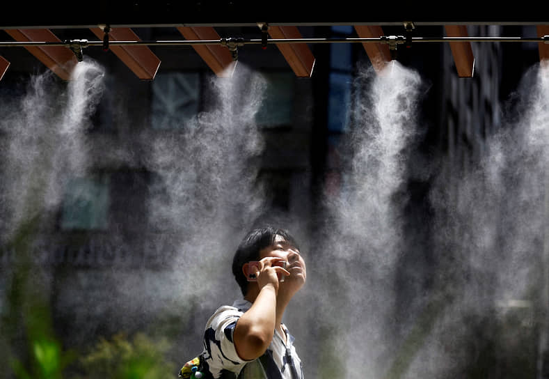 Токио. Мужчина спасается от жары под системой охлаждения туманом
