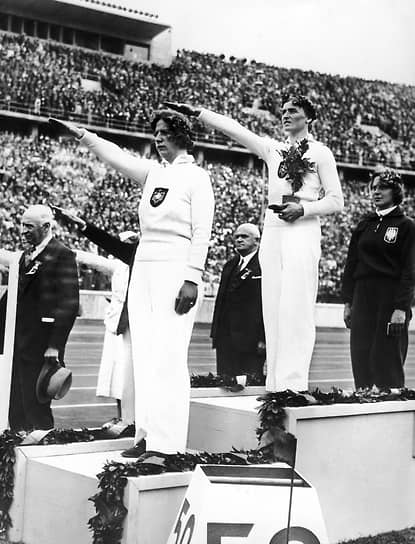 Бронзовый призер и олимпийская чемпионка Паула Молленхауэр (слева) и Гизела Мауэрмайер на пьедестале вскидывают руки в нацистском приветствии 