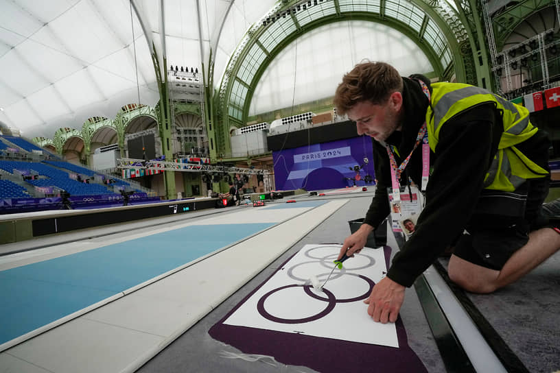Волонтер рисует олимпийские кольца в одном из залов Большого дворца («Гран-Пале») в Париже, где будут проходить соревнования по фехтованию и тхэквондо