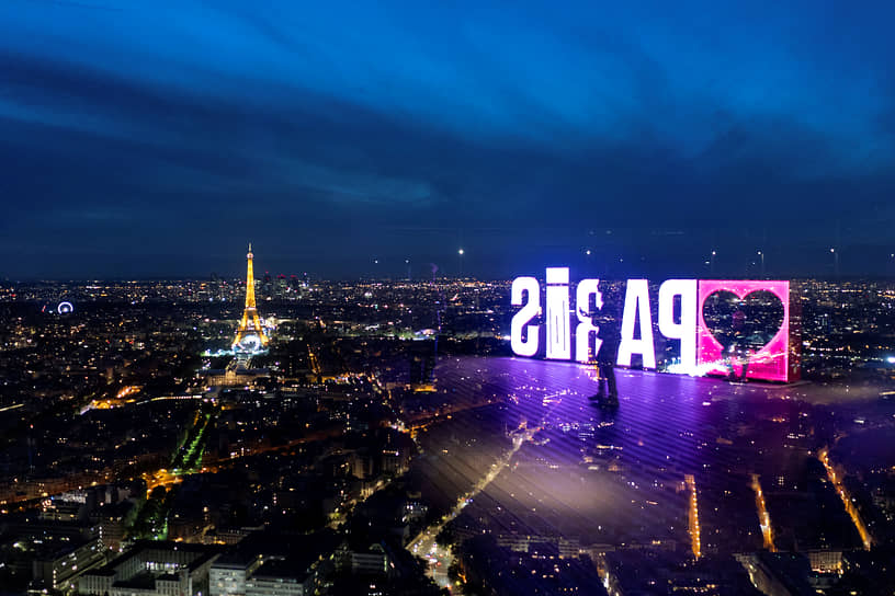 Надпись «Париж» отражается в стеклянной стене смотровой площадки башни Монпарнас