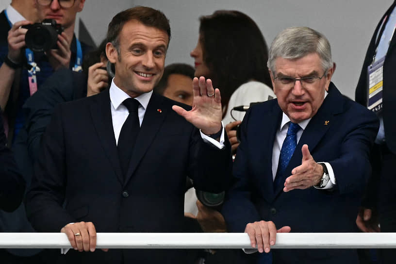 Президент Франции Эмманюэль Макрон (слева) и глава Международного олимпийского комитета Томас Бах приветствуют спортсменов и гостей Олимпиады 