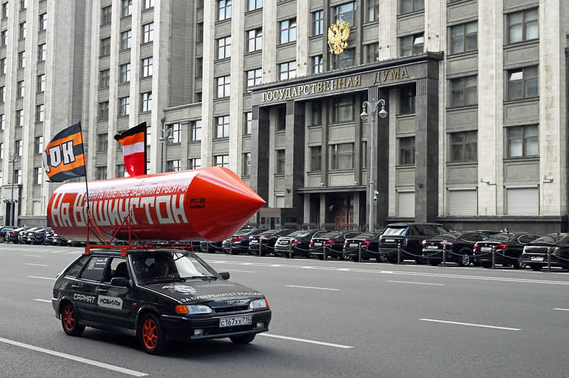 Москва. Автомобиль с бутафорской ракетой с надписью «На Вашингтон, вернуть полетные задания РВСН РФ» проезжает мимо здания Госдумы