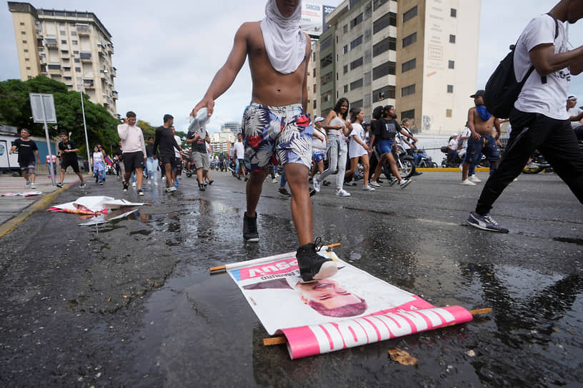 Некоторые из протестующих срывали со столбов агитационные плакаты президентской кампании Николаса Мадуро, сжигали их и бросали камни в сторону сотрудников полиции