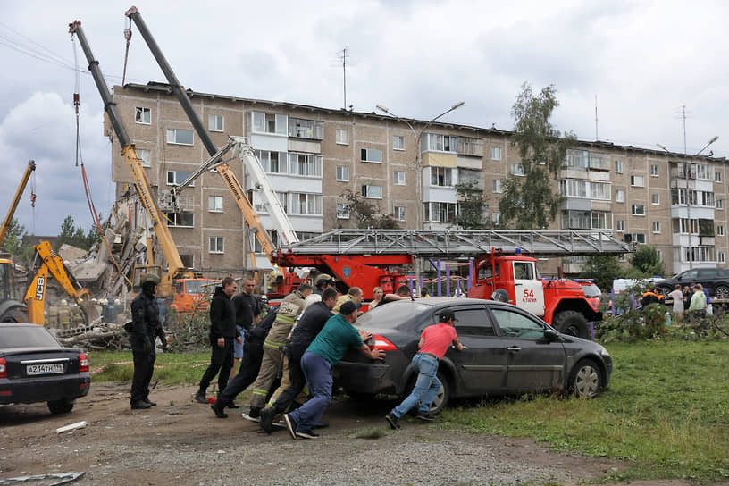 Спасатели МЧС вручную оттаскивают машины, мешающие технике и людям разбирать перекрытия и другие конструкции дома