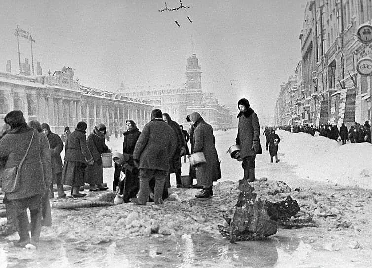 Жители блокадного Ленинграда в очереди за водой к пробитому при налете водопроводу, декабрь 1941 года