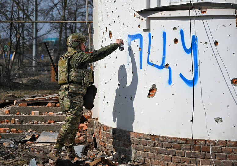 Военнослужащий закрашивает надпись ПЦУ (Православная церковь Украины) на фасаде Дмитриевской церкви