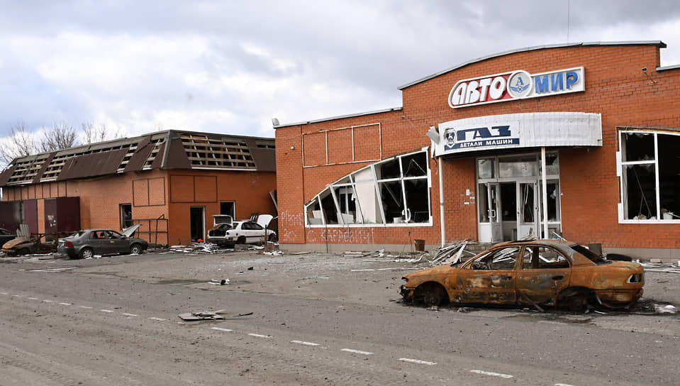 Поврежденные здания магазинов и сожженный автомобиль