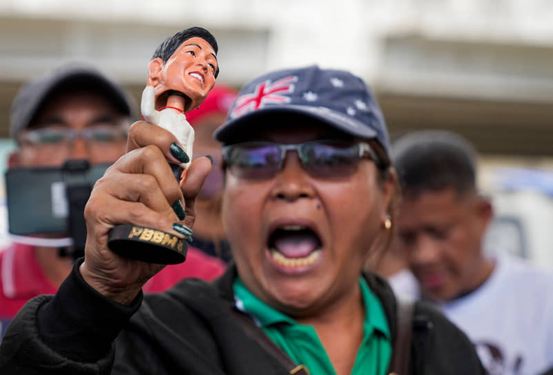 Участник демонстрации протеста против ареста экс-президента Дутерте с фигуркой президента Фердинанда Маркоса-младшего