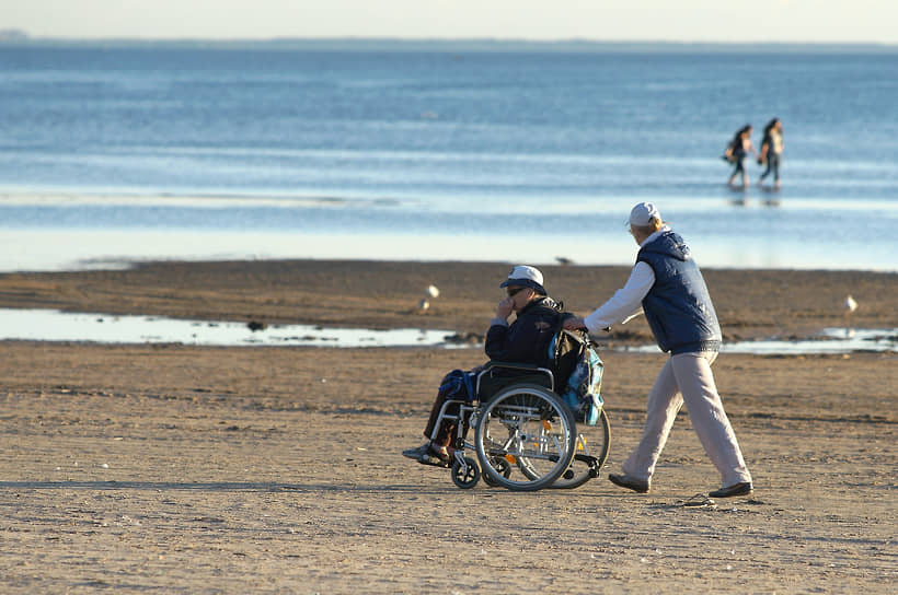 An assistant walking with his charge on the shore of the Gulf of Finland