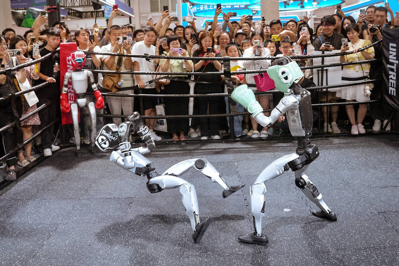 Зрители наблюдают за боем гуманоидных роботов на стенде компании Unitree Robotics