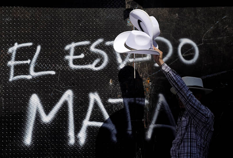 Мужчина на фоне граффити «Государство убивает»