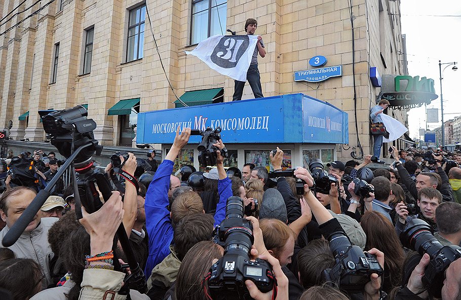 Участник акции "Стратегия-31" в защиту свободы собраний с плакатом "31" на крыше киоска на Триумфальной площади