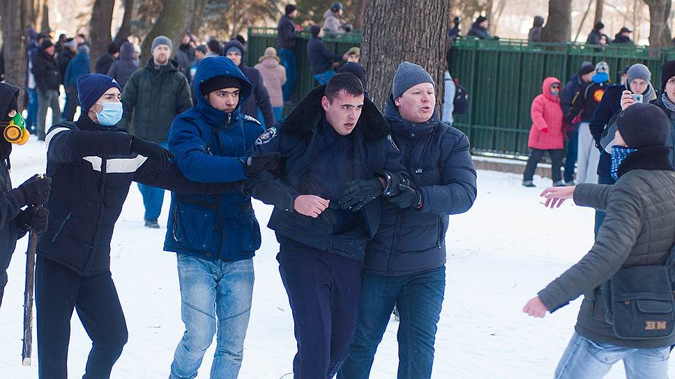Митингующие ведут милиционера возле здания Днепропетровской областной государственной администрации для оказания медицинской помощи