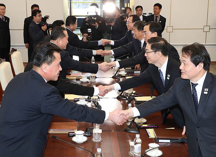 Члены официальных делегаций Южной Кореи (справа) и КНДР обменялись первыми рукопожатиями за два года