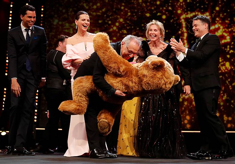 Директор Берлинского кинофестиваля Дитер Косслик (в центре) держит медведя, врученного председателем жюри Жюльетт Бинош (слева)