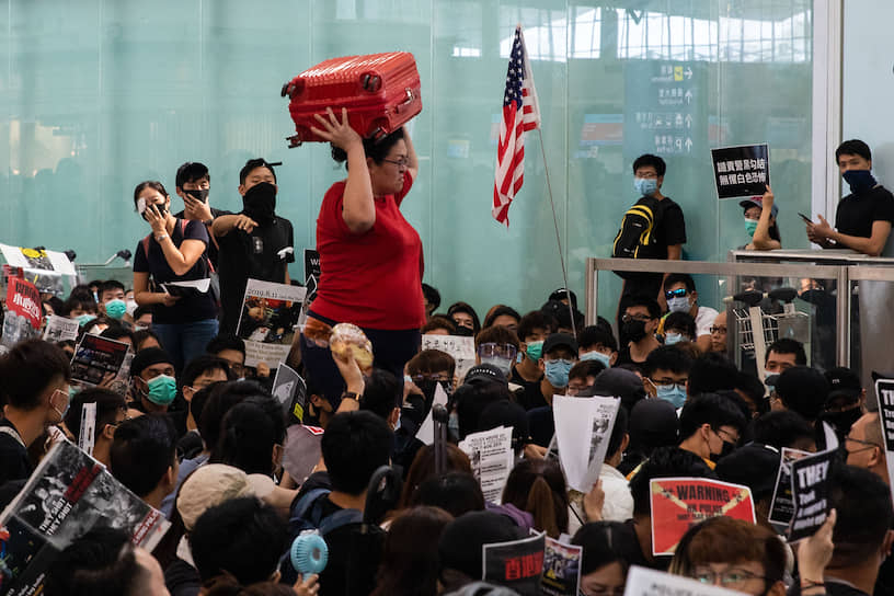 В аэропорту Гонконга пассажирам приходится с боем прорываться к стойкам регистрации, заблокированным протестующими