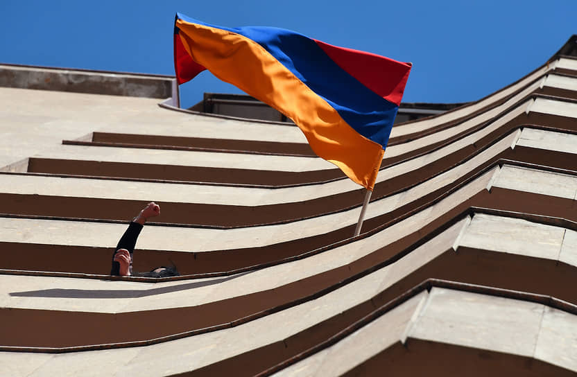 Жители города на балконе дома с государственным флагом Армении во время марша оппозиции 