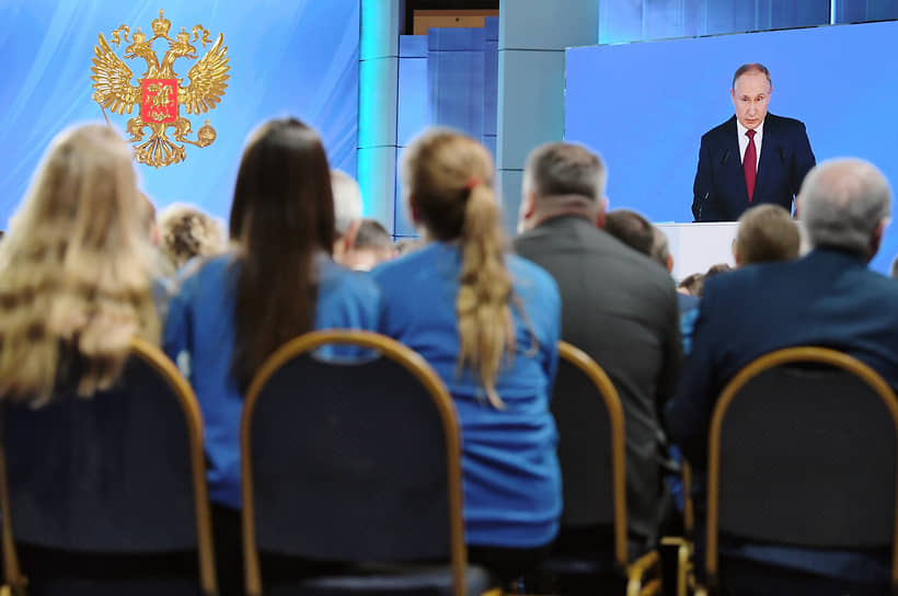 Президент России Владимир Путин (на экране) во время ежегодного Послания Федеральному Собранию