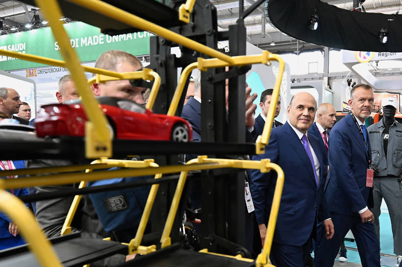 Директор деловой программы выставки «Иннопром» Антон Атрашкин (справа) и председатель правительства России Михаил Мишустин во время осмотра выставки «Иннопром 2025».