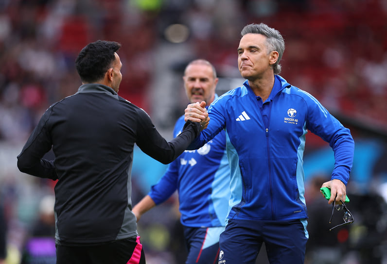 Жмет руку футболисту Карлосу Тевесу перед благотворительным матчем Soccer Aid в поддержку ЮНИСЕФ в Манчестере, 2025 год