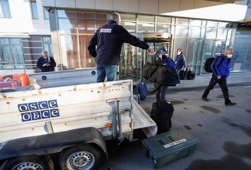 Сотрудники ОБСЕ грузят багаж на выходе из отеля