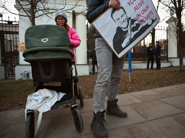 Человек стоит у посольства России в Варшаве (Польша), держа в руках табличку с надписью «Ты жив в наших сердцах»
