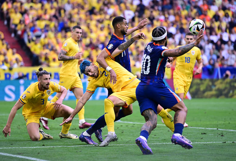 Борьба за мяч между футболистами сборных Нидерландов и Румынии