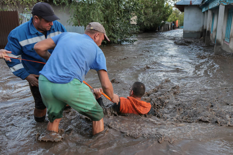 Местные жители и спасатели вытаскивают мужчину из воды в коммуне Слобозия-Конаки (Румыния)