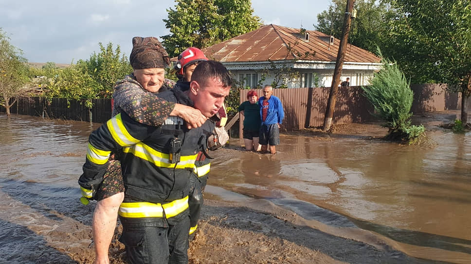 Пожарный эвакуирует женщину в коммуне Пече (Румыния)