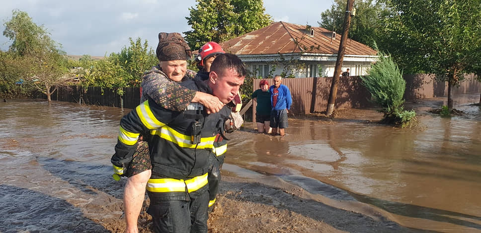 Пожарный эвакуирует женщину в коммуне Пече (Румыния)