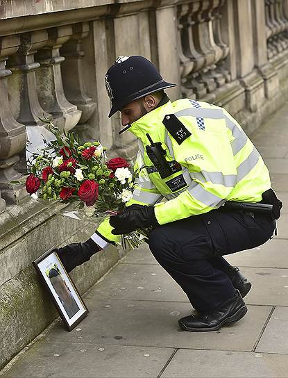 Полицейские приносят цветы к месту, где был убит их коллега 
