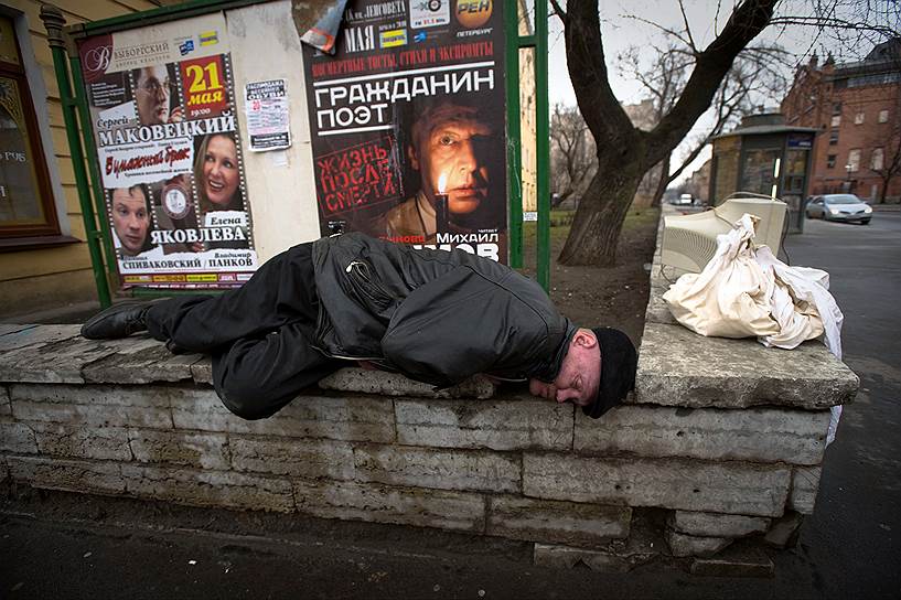 Бездомный спит на уличном парапете на улице Декабристов. Всего в Санкт-Петербурге примерно 60 тысяч бездомных
