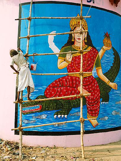 Местный художник рисует на стене изображение индийского божества