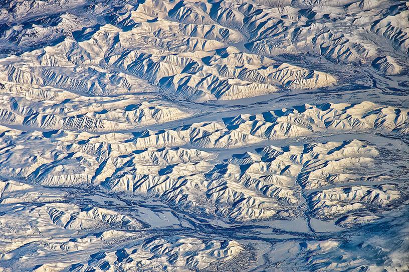 Камчатские зарисовки. Камчатка — это не только гейзеры и вулканы. В этом заповедном крае множество горных хребтов с впечатляющими ландшафтами по всей длине полуострова. На этом снимке с МКС запечатлен Срединный хребет под снежным покровом в районе реки Хайлюля, снятый в марте 2014 года  

