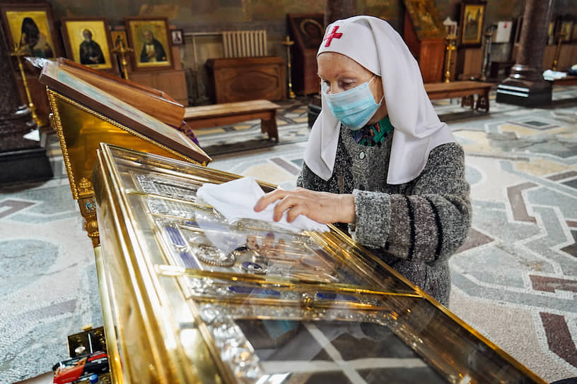 Пока монахи молятся об избавлении от пандемии, сотрудница Свято-Троицкой Сергиевой Приморской пустыни Санкт-Петербургской епархии обрабатывает иконы дезинфицирующим раствором