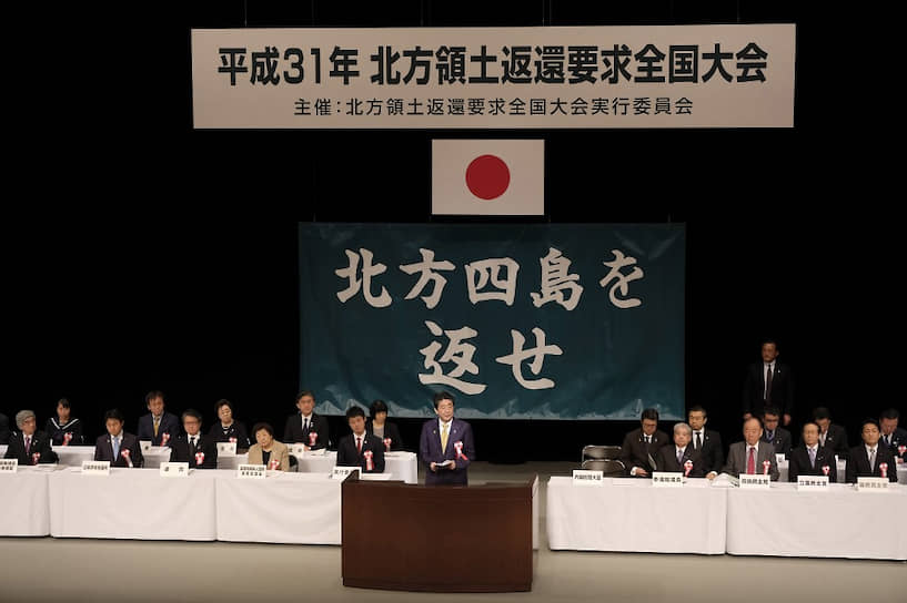 7 февраля прошлого года, Токио. Премьер-министр Абэ выступает на мероприятии, посвященном официальной календарной дате — «Дню северных территорий». Тут все без дипломатии и никаких компромиссных вариантов: висящий над трибуной лозунг требует вернуть Японии спорные острова — все четыре