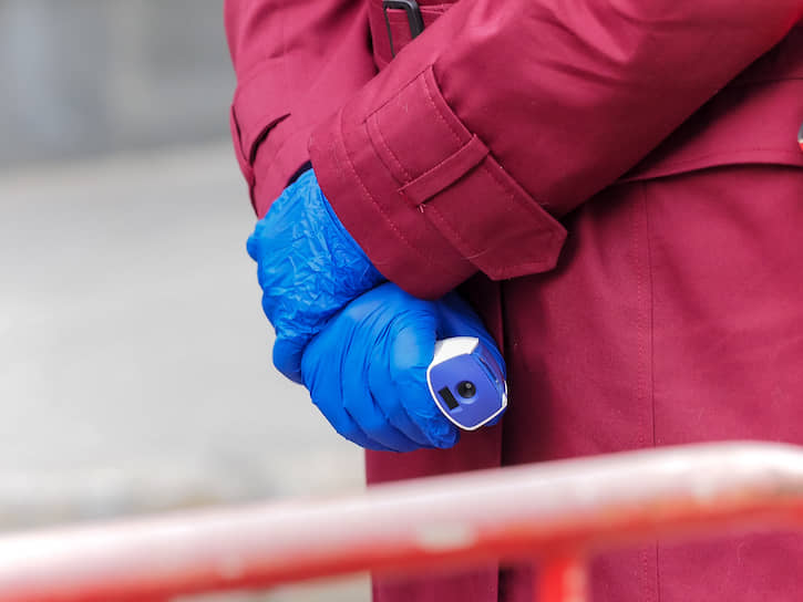 Сотрудник Роспотребнадзора в перчатках с бесконтактным термометром